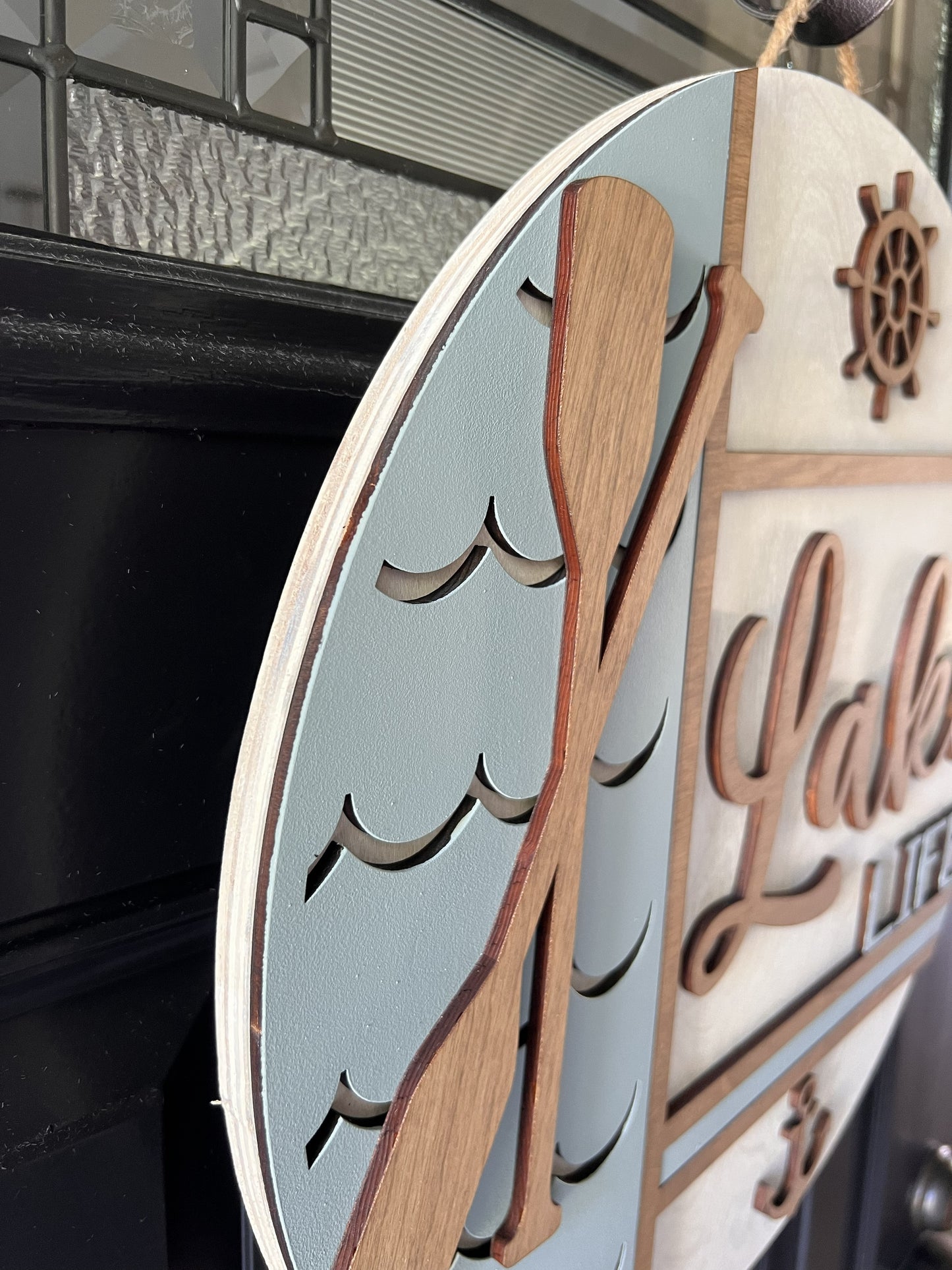Decorative wall art  with wooden paddle and ship wheel design on a birchwood round hanger
