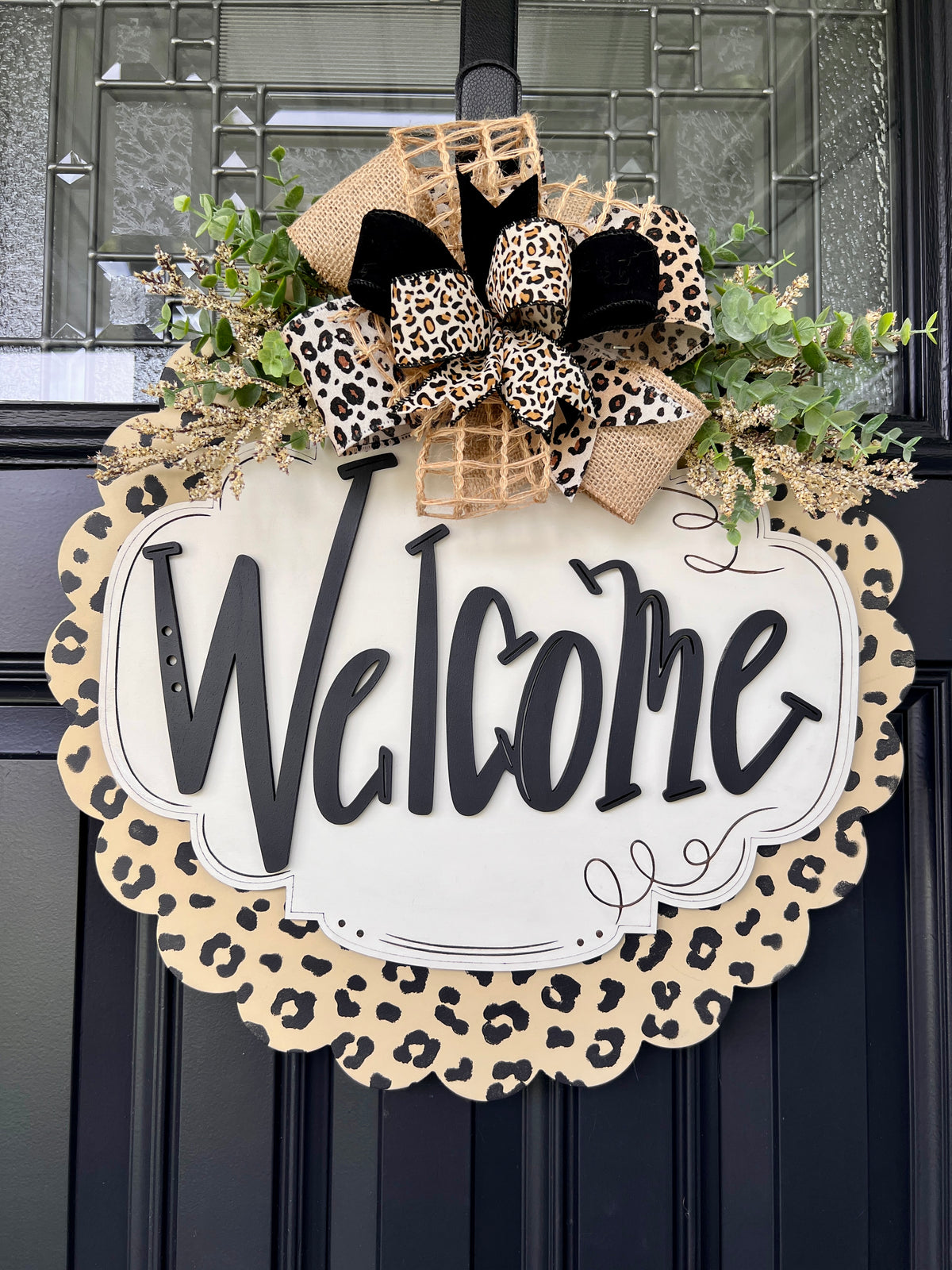 Leopard scalloped Welcome door hanger with burlap and black bow hanging on a black front door