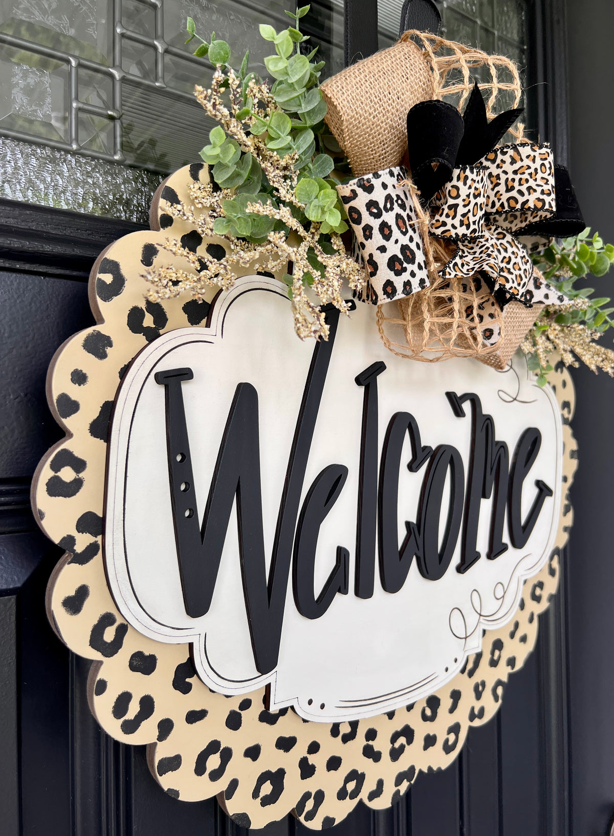 Close-up of leopard print bow with burlap and faux greenery on Welcome door hanger