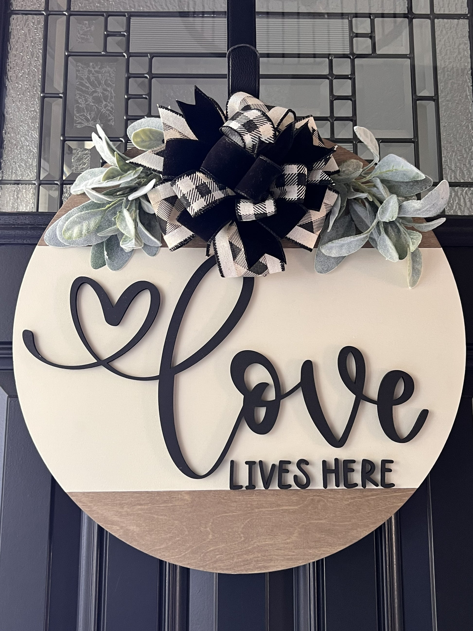 Decorative sign with 'Love Lives Here' text and floral elements on a front door.
