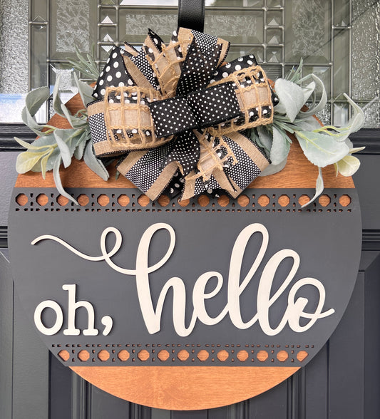 Oh hello door hanger close up detail showing cream script lettering depth and charcoal background texture with rattan border accent