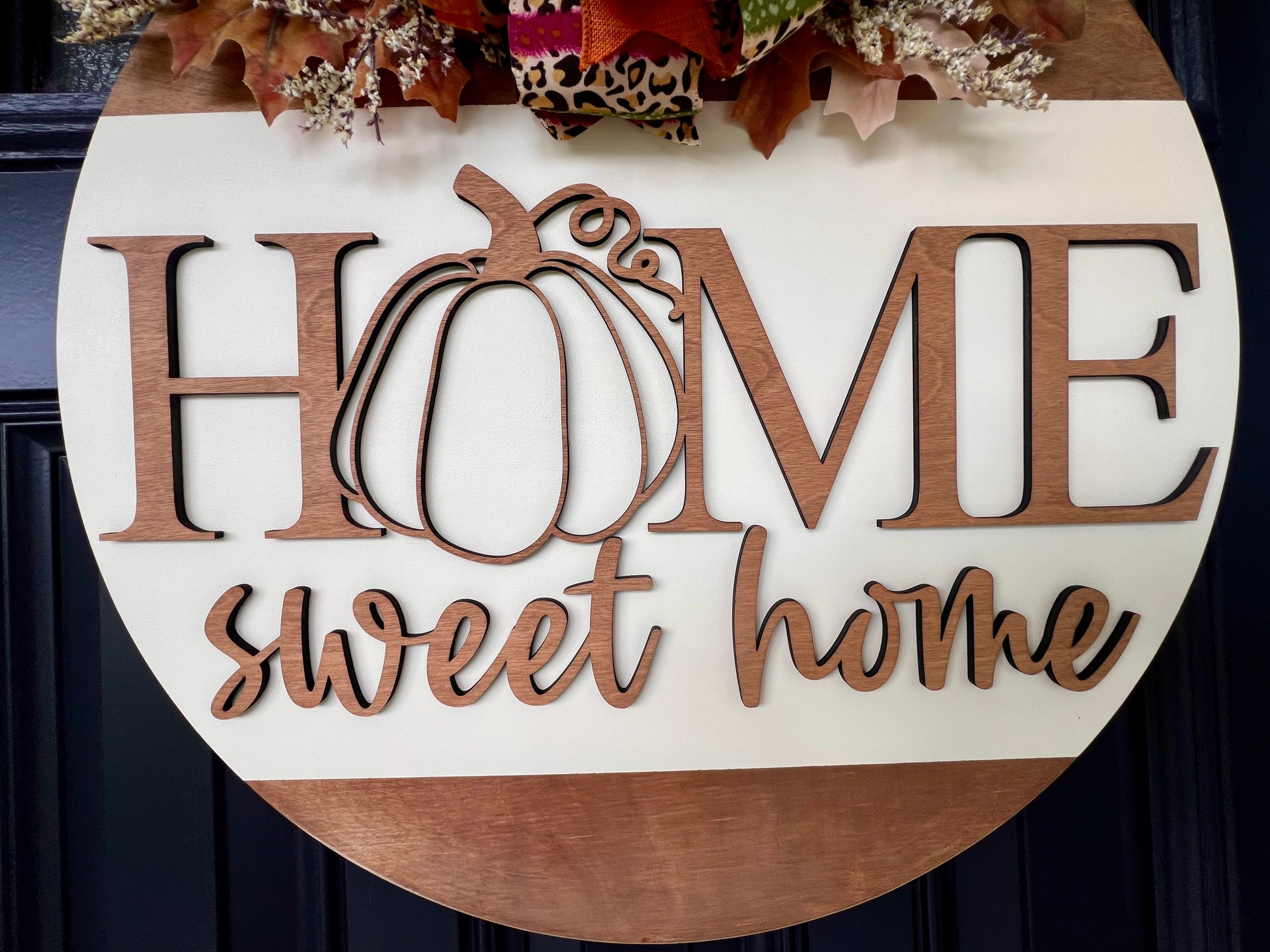 Decorative sign with 'HOME sweet home' birchwood overlay and pumpkin design on a warm white/stained doorhanger.