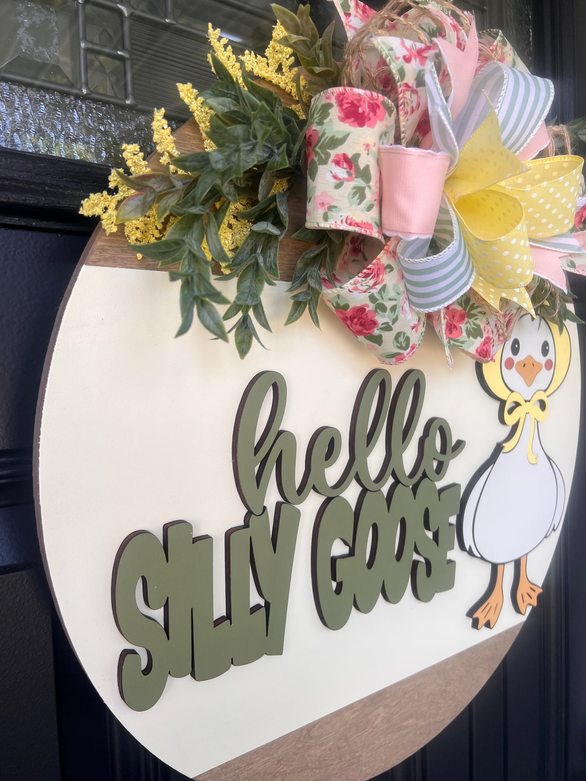 Decorative sign with 'hello silly goose' text and a goose illustration on a wooden background.