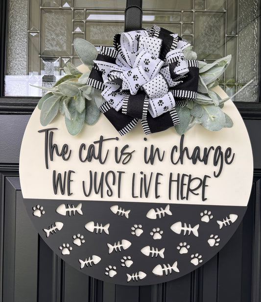 The Cat is in Charge We Just Live Here door hanger on black front door with paw print bow and lambs ear greenery