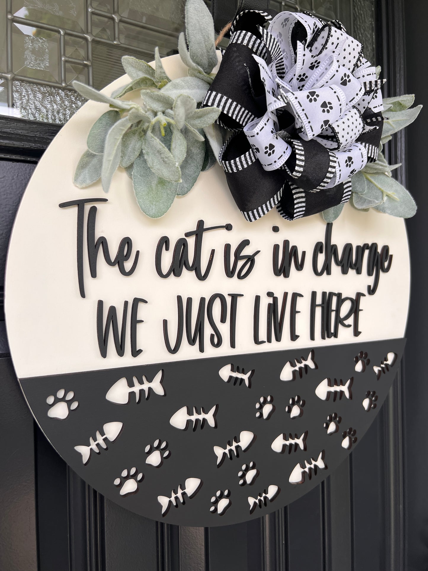 The Cat is in Charge door hanger close up of 3D script lettering and laser-cut white paw prints and fish bones on charcoal panel