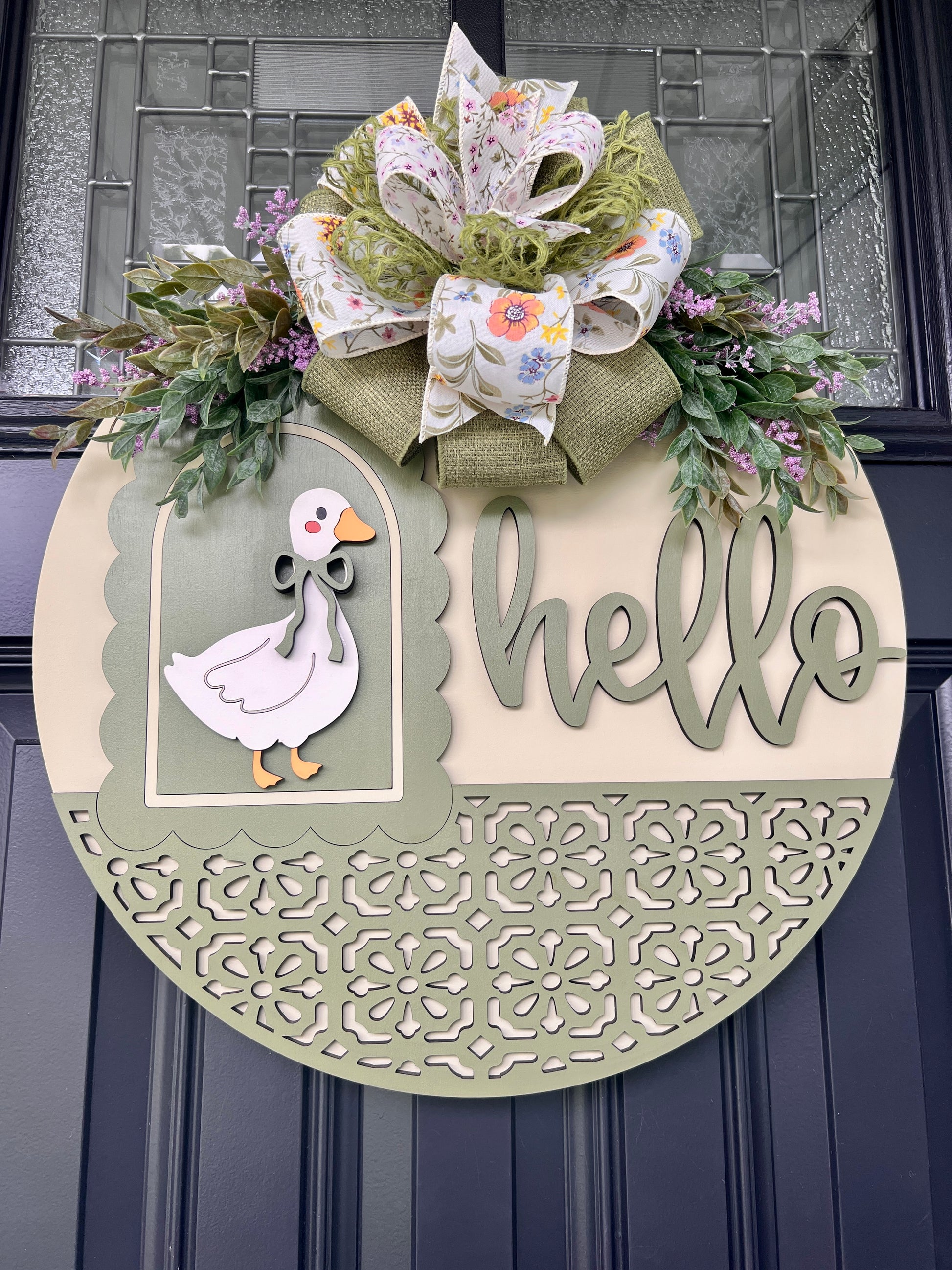 Round farmhouse Hello goose front door sign featuring layered laser-cut wood, decorative cutout border, vintage goose artwork, and a handcrafted floral ribbon bow.