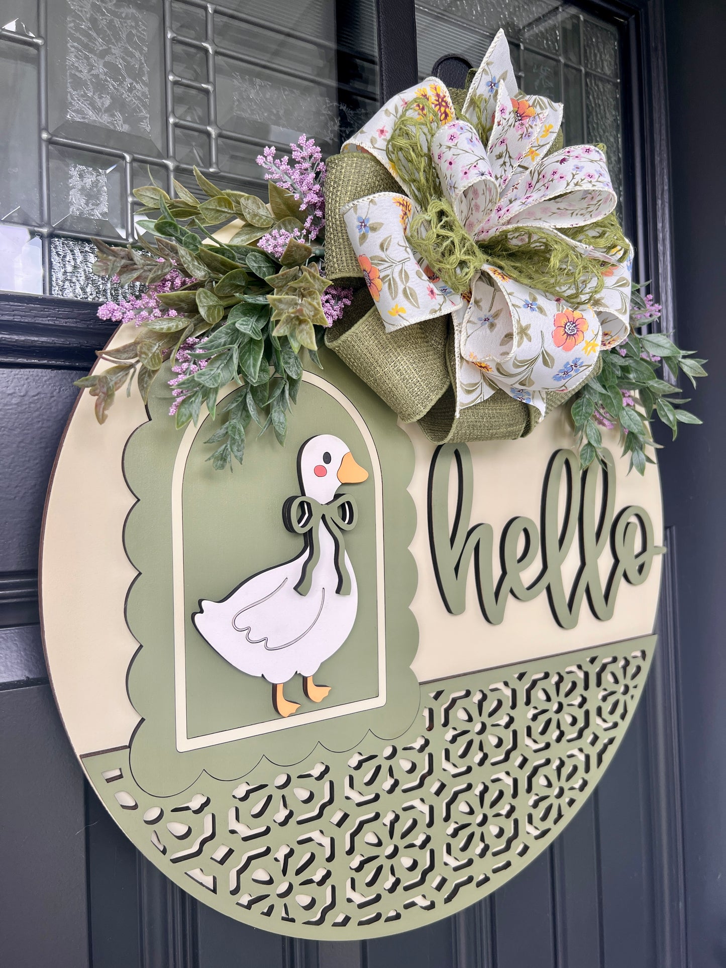 Side profile of a layered Hello goose wooden door hanger featuring a vintage goose, sage green accents, premium floral bow, and lush spring greenery for farmhouse front porch décor.