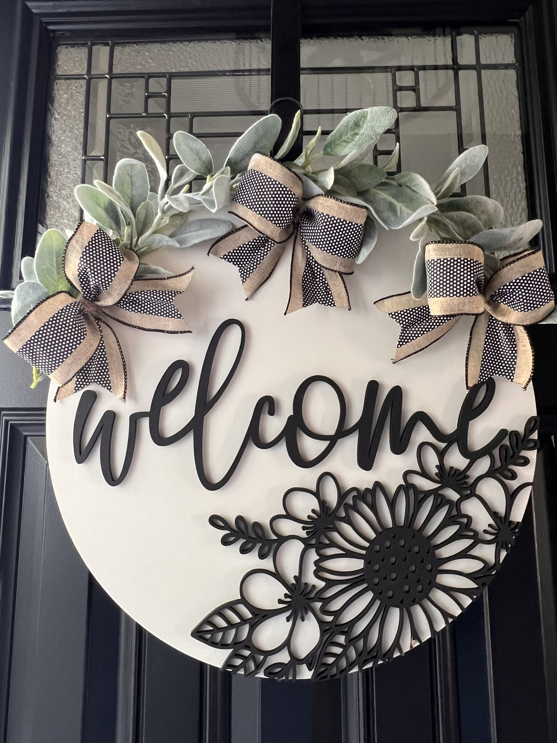 neutral floral welcome door hanger with black 3-D raised floral design, bows and greenery