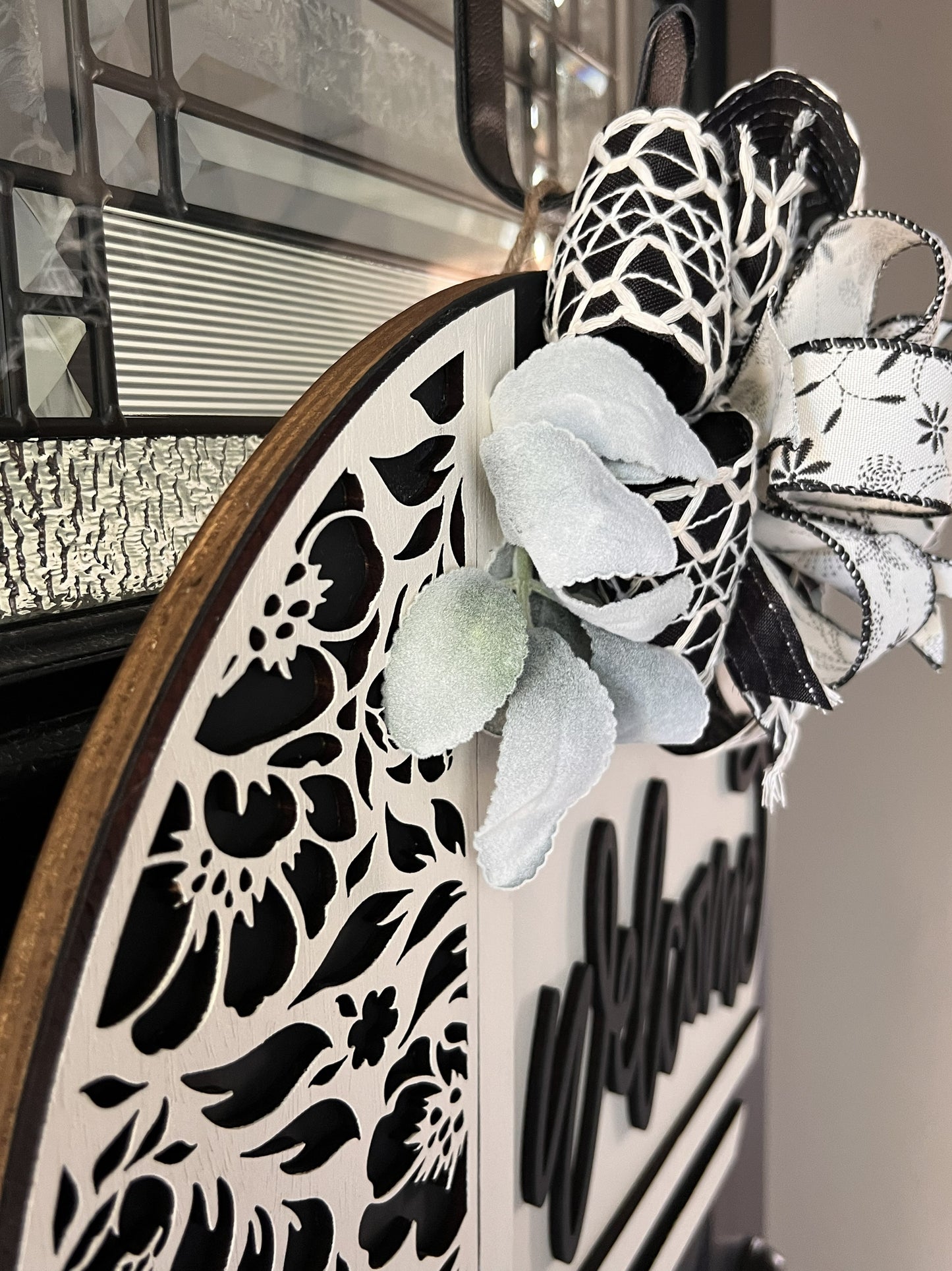 Decorative door hanger wreath with floral patterns and a designer bow on a door