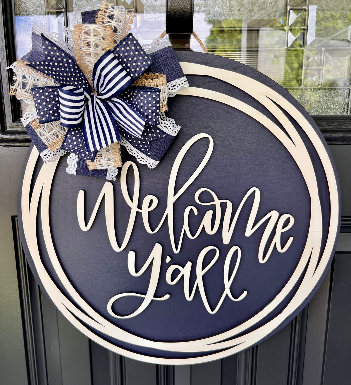 Welcome Y'all 18" round navy and cream circle frame door hanger with layered bow - front view on black door