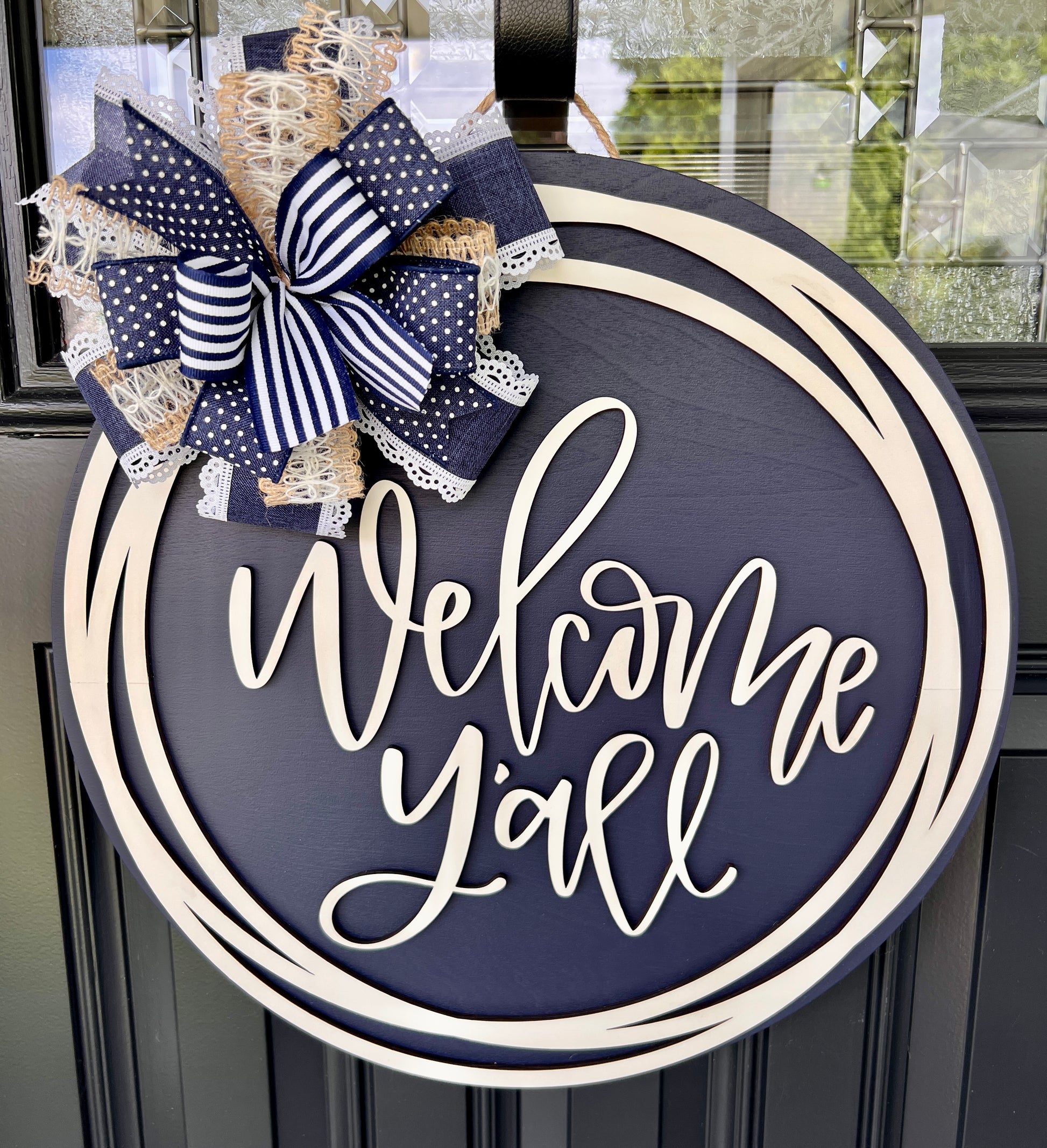Welcome Y'all 18" round navy and cream circle frame door hanger with layered bow - front view on black door