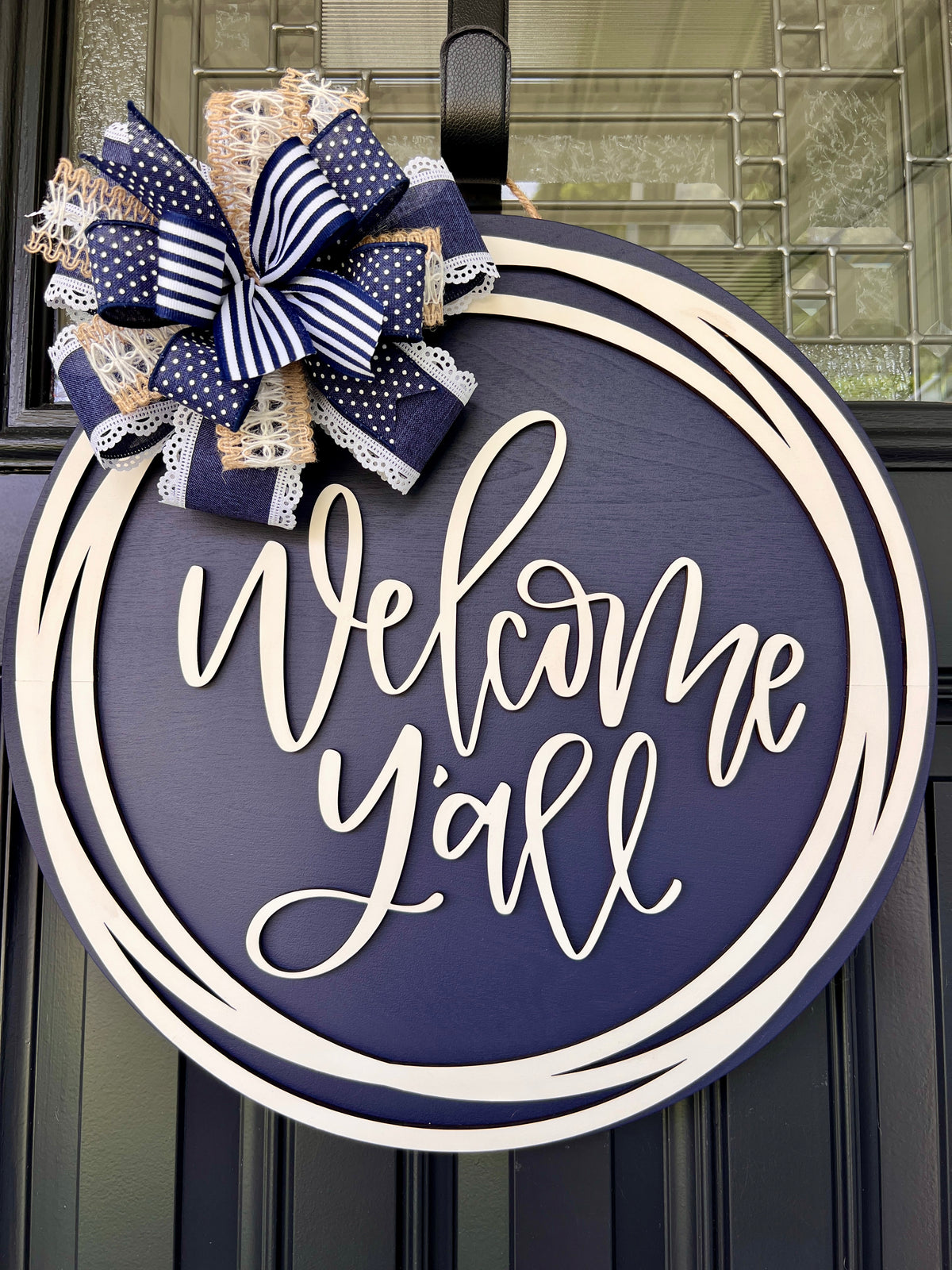 Welcome Y'all navy circle door hanger with navy stripe and polka dot bow - angled view