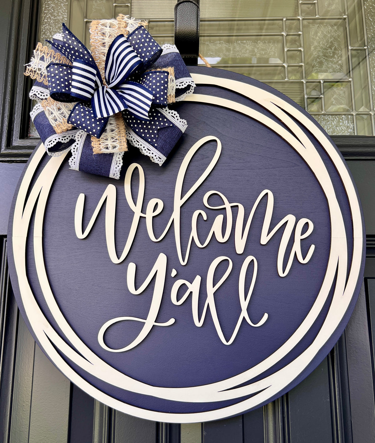Welcome Y'all door hanger close up showing 3D cream lettering on navy background