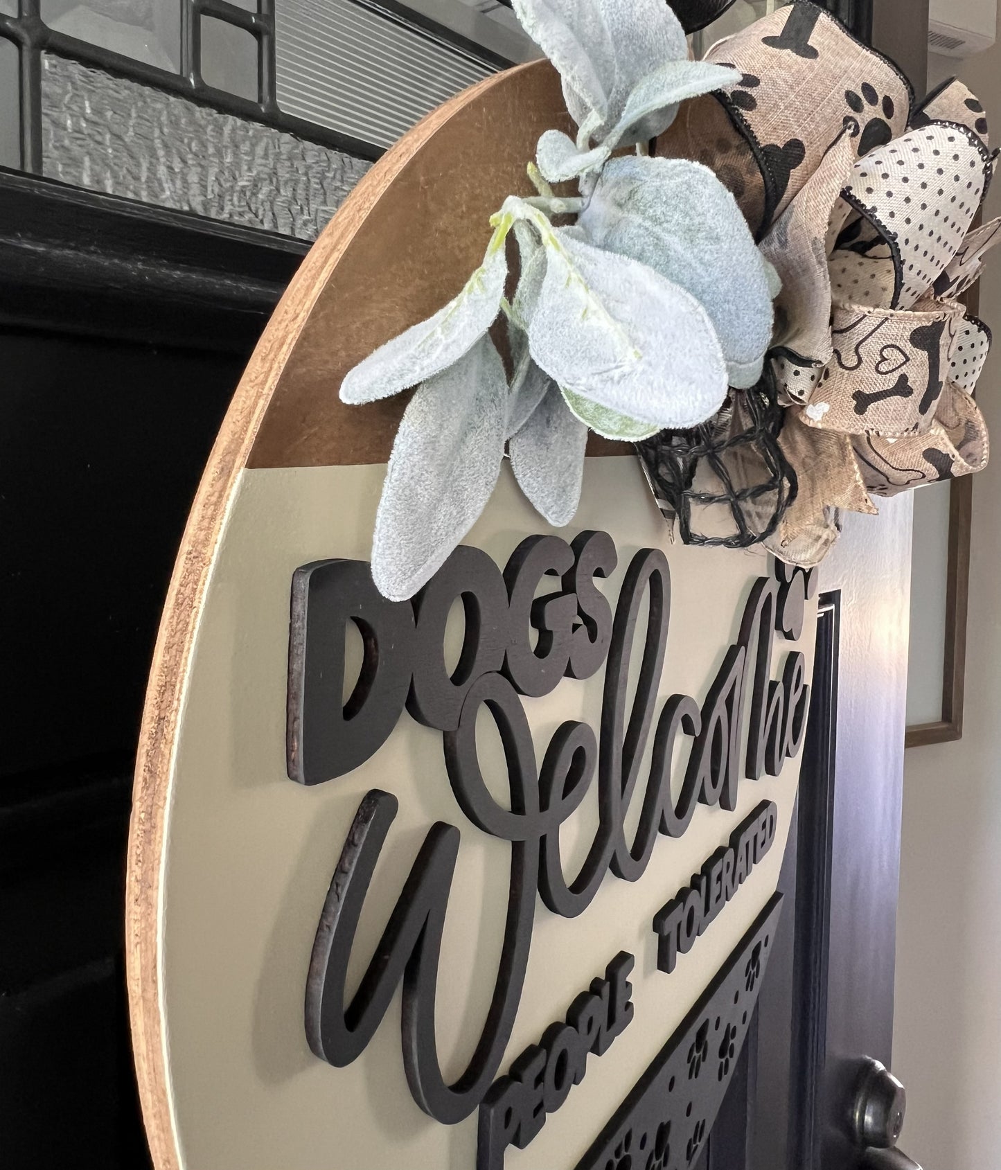 Decorative sign with 'Dog Welcome' text and floral elements on a door.