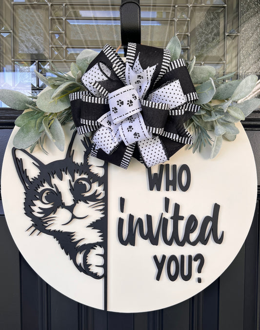 Funny cat door hanger featuring a black cat peeking around the edge and the phrase "Who Invited You?" displayed on a front door.