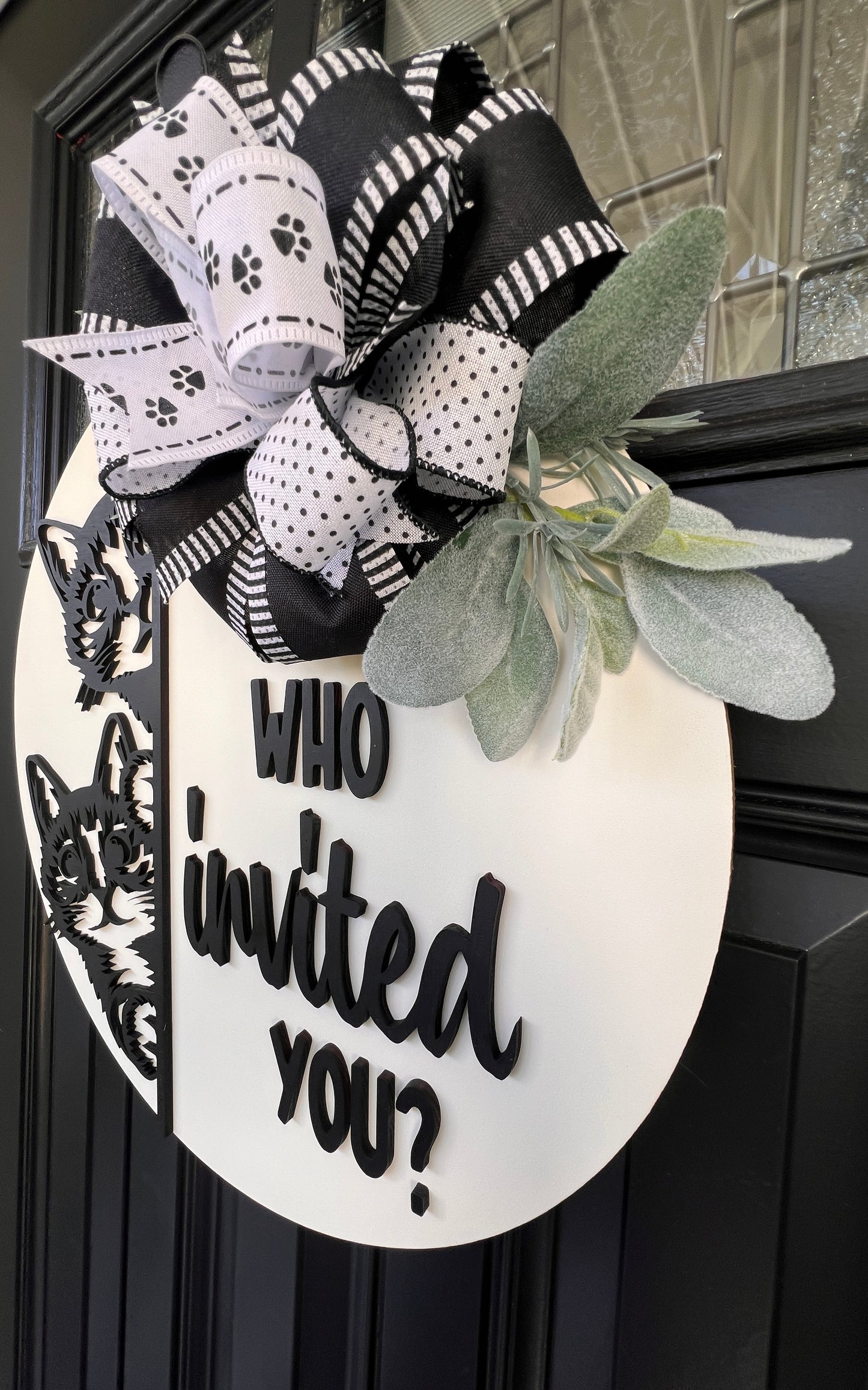 "Black and white cat-themed wooden door hanger with two cats and the phrase 'Who Invited You?' displayed on a front door."