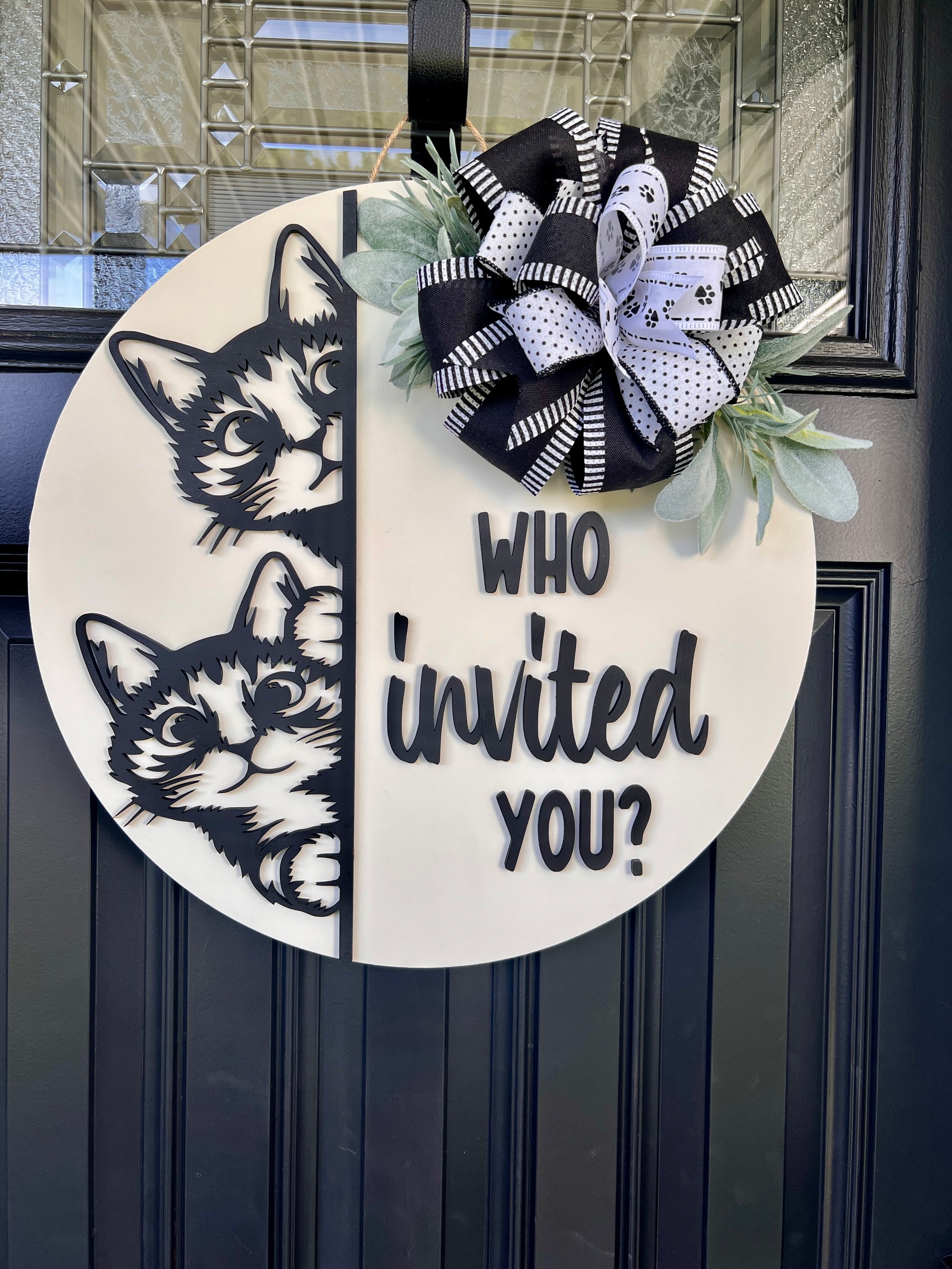 "Black and white cat-themed wooden door hanger with two cats and the phrase 'Who Invited You?' displayed on a front door."
