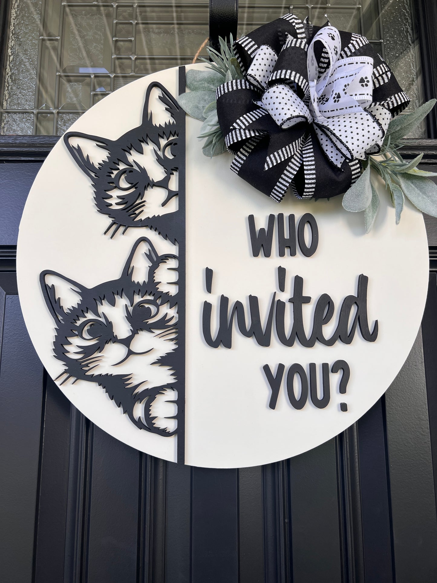 "Black and white cat-themed wooden door hanger with two cats and the phrase 'Who Invited You?' displayed on a front door."