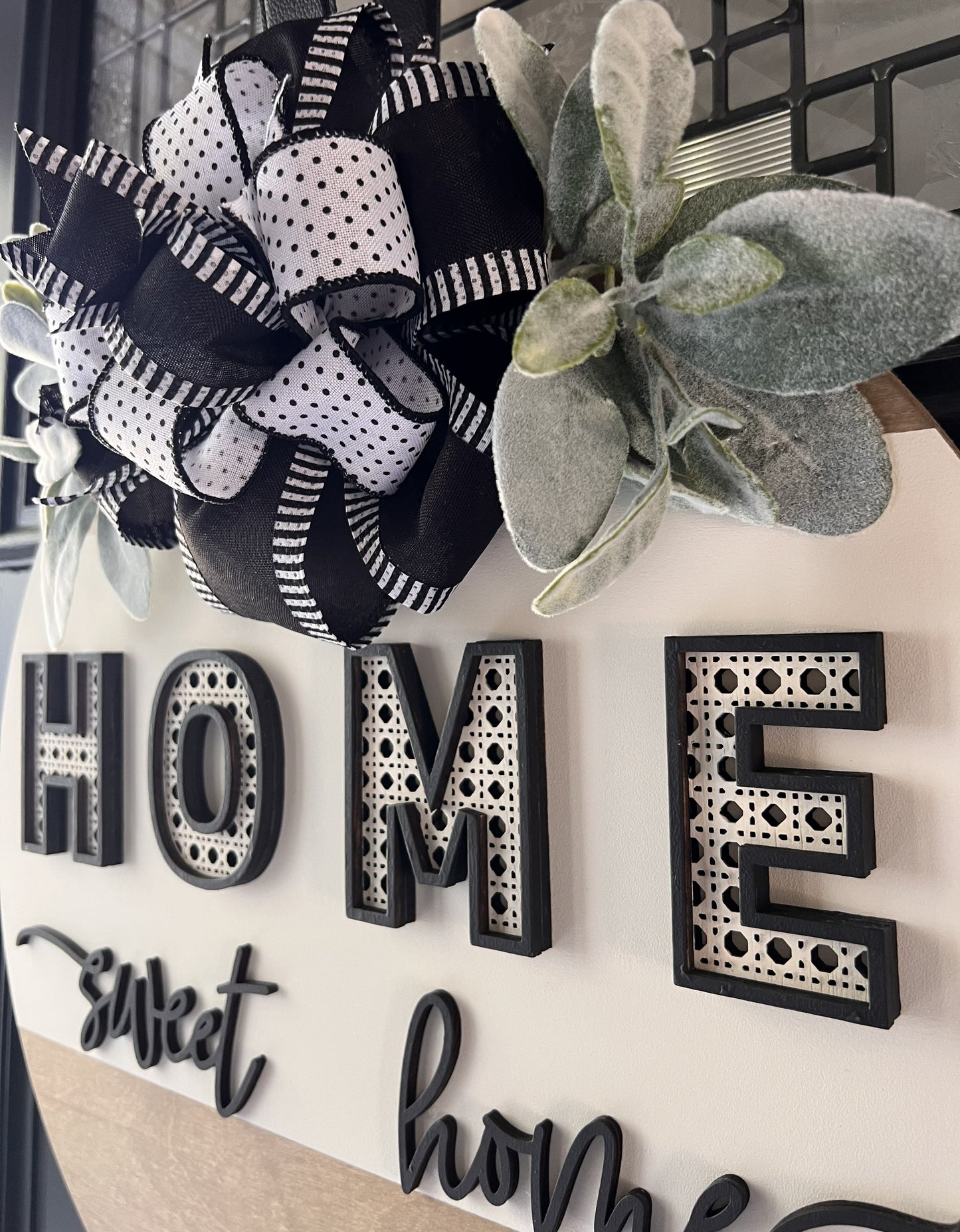 Decorative wall art with 'HOME sweet home' text and black and white polka dot bow.