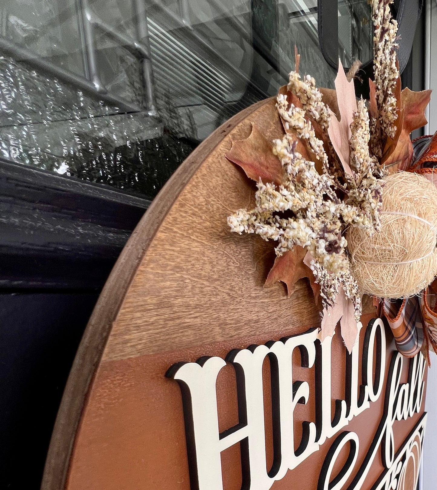 Hello Fall pumpkin door hanger with layered wood lettering, decorative pumpkin cutouts, designer bow, seasonal greenery, and autumn accents displayed on a front door