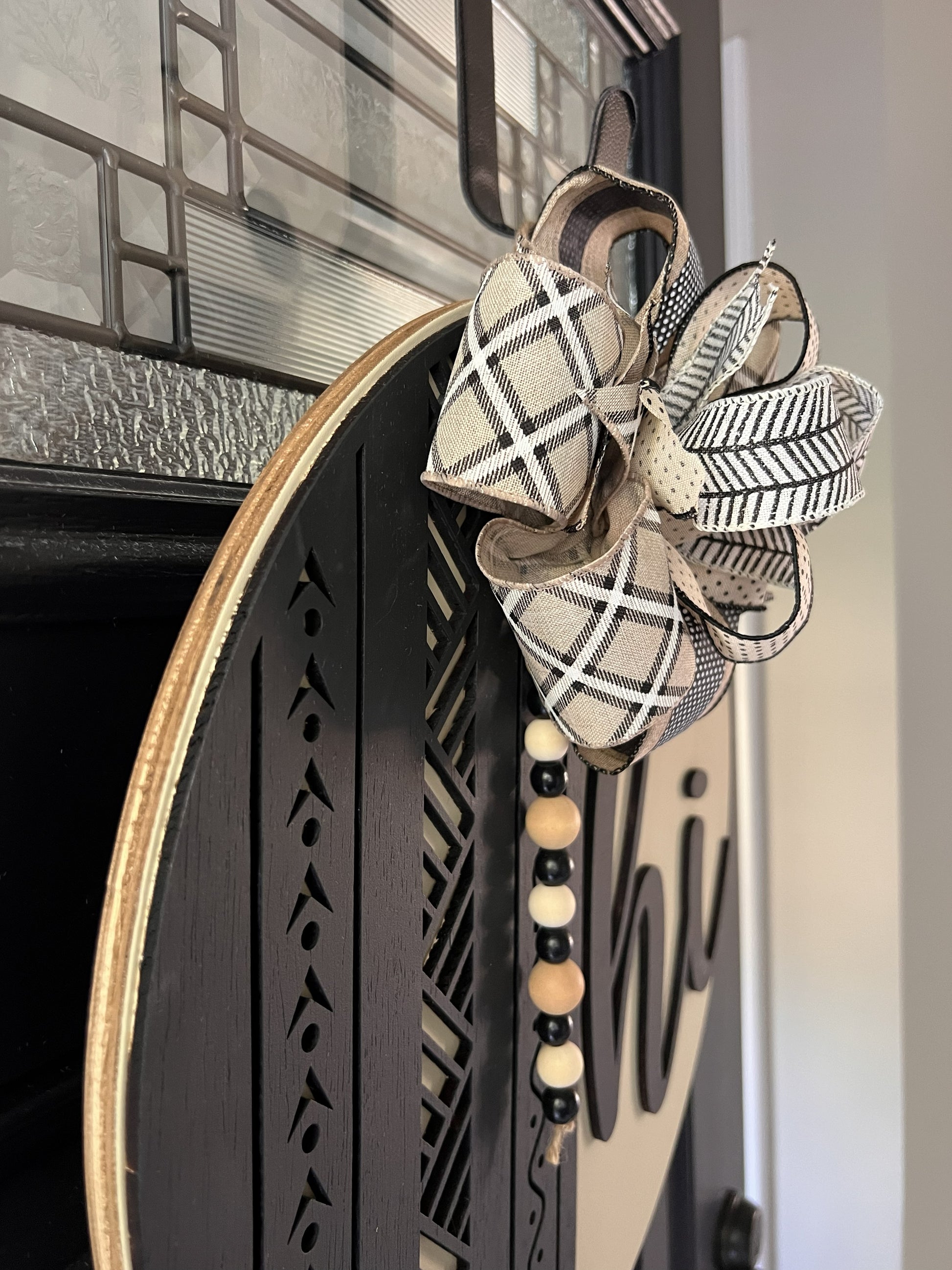 Decorative wreath with a designer plaid bow and beaded tassel on a birchwood door hanger. 