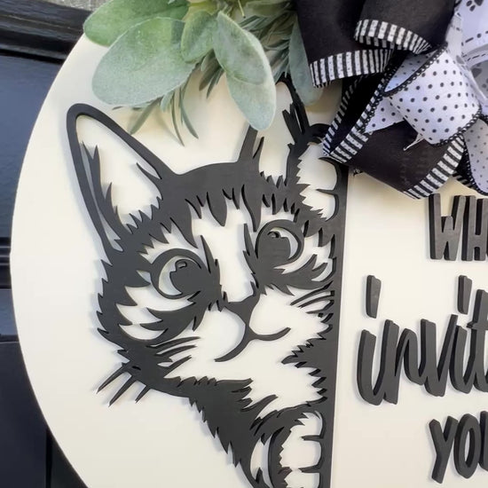 Funny cat door hanger featuring a black cat peeking around the edge and the phrase "Who Invited You?" displayed on a front door.