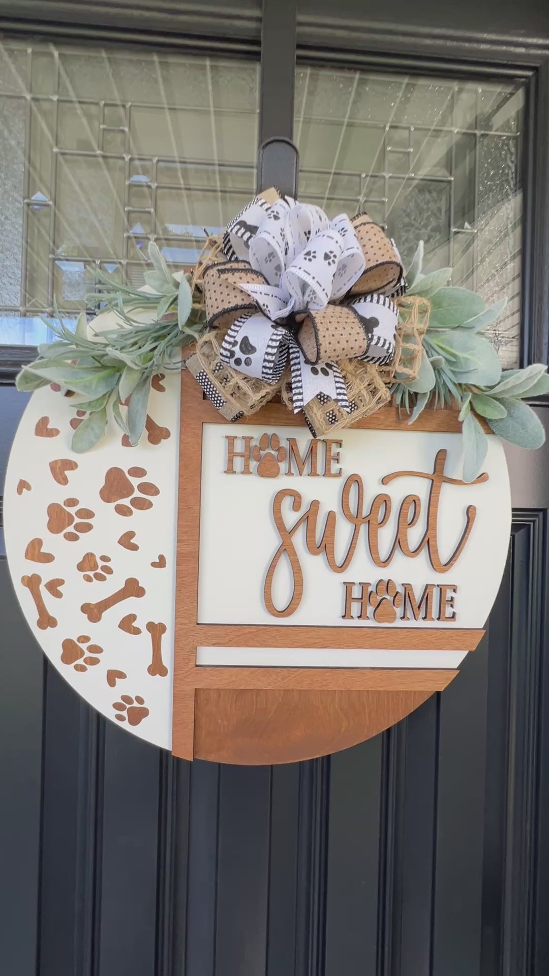 Handmade Home Sweet Home dog lover door hanger featuring laser-cut paw prints, dog bone accents, stained birchwood details, greenery, and a coordinating designer bow.