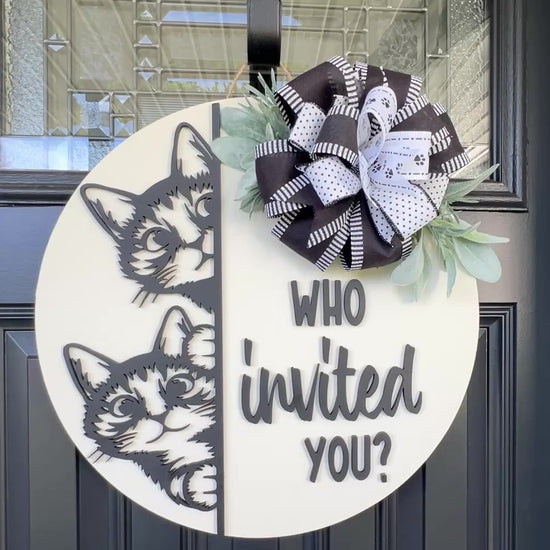 "Black and white cat-themed wooden door hanger with two cats and the phrase 'Who Invited You?' displayed on a front door."