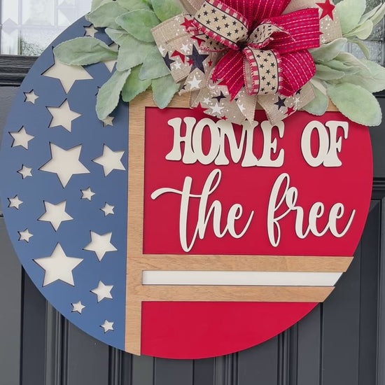 Decorative door hanger with 'Home of the Free' text and American flag design.