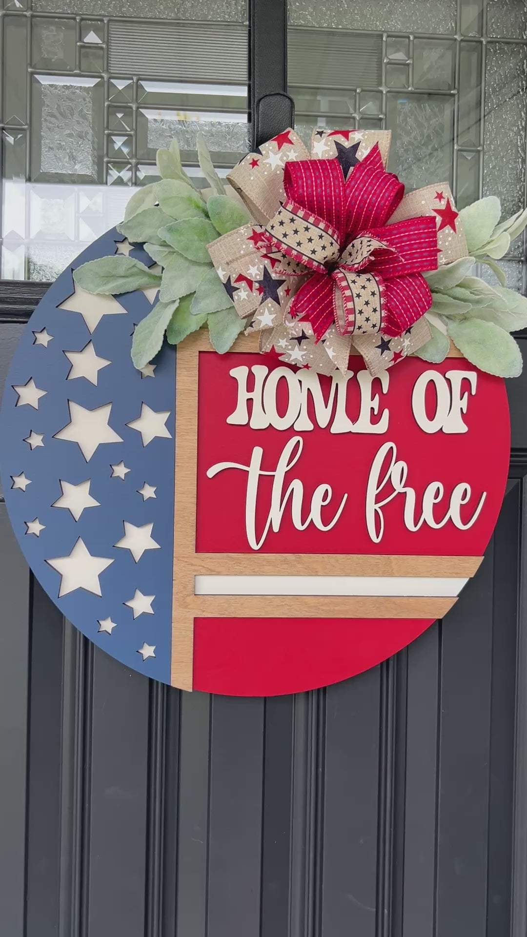 Decorative door hanger with 'Home of the Free' text and American flag design.