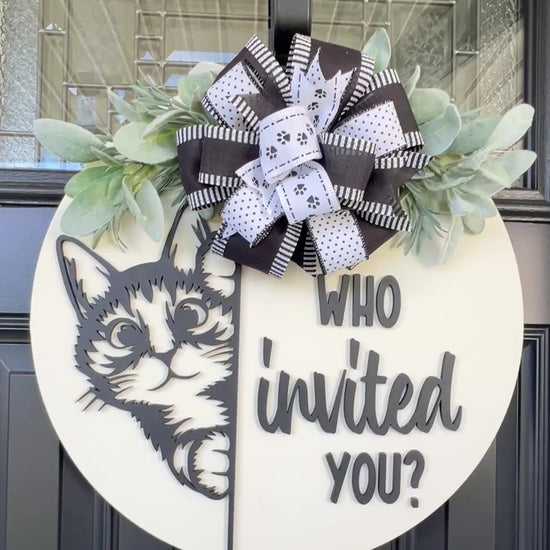 Funny cat door hanger featuring a black cat peeking around the edge and the phrase "Who Invited You?" displayed on a front door.