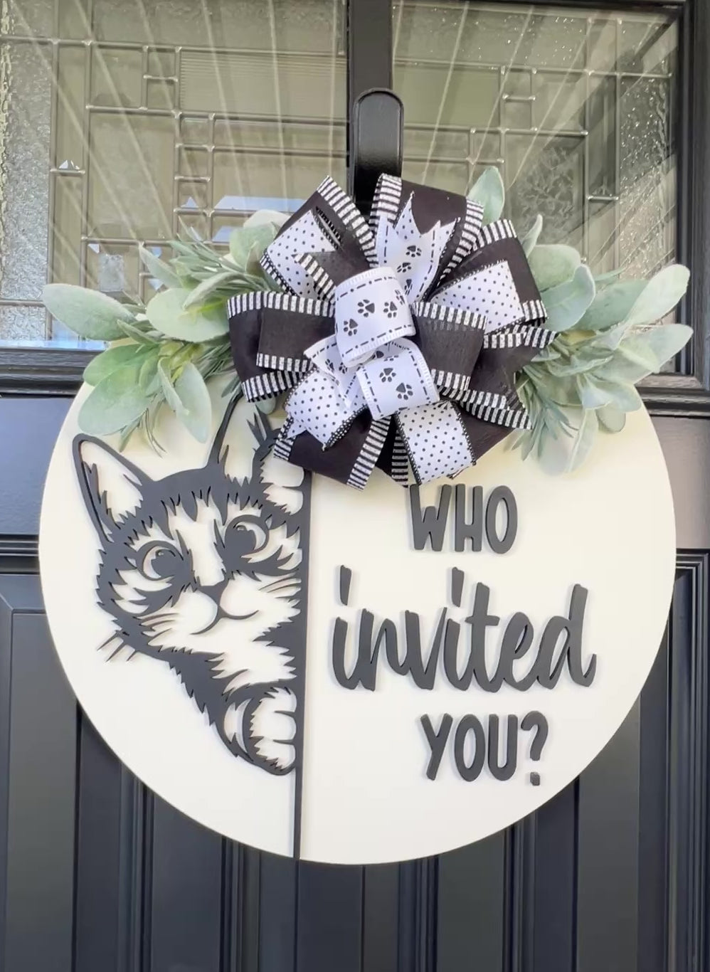 Funny cat door hanger featuring a black cat peeking around the edge and the phrase "Who Invited You?" displayed on a front door.