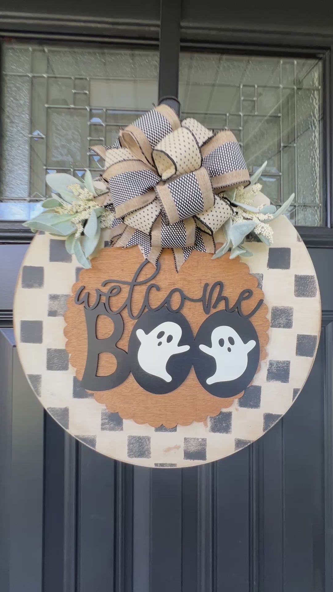 Handmade Welcome Boo Halloween door hanger with ghost accents, black and cream checkered background, layered wood lettering, designer bow, and fall front porch décor.