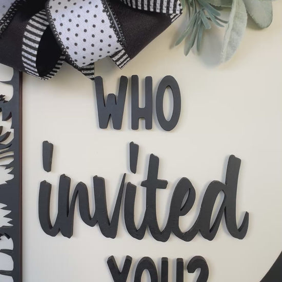 Funny cat door hanger featuring a black cat peeking around the edge and the phrase "Who Invited You?" displayed on a front door.