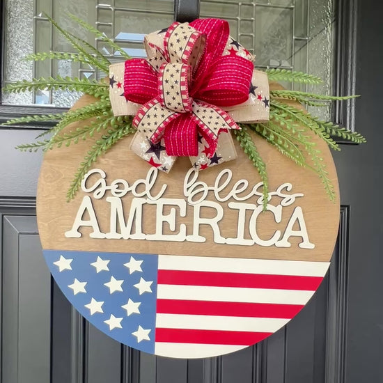 Decorative door hanger with 'God bless America' text and American flag design.