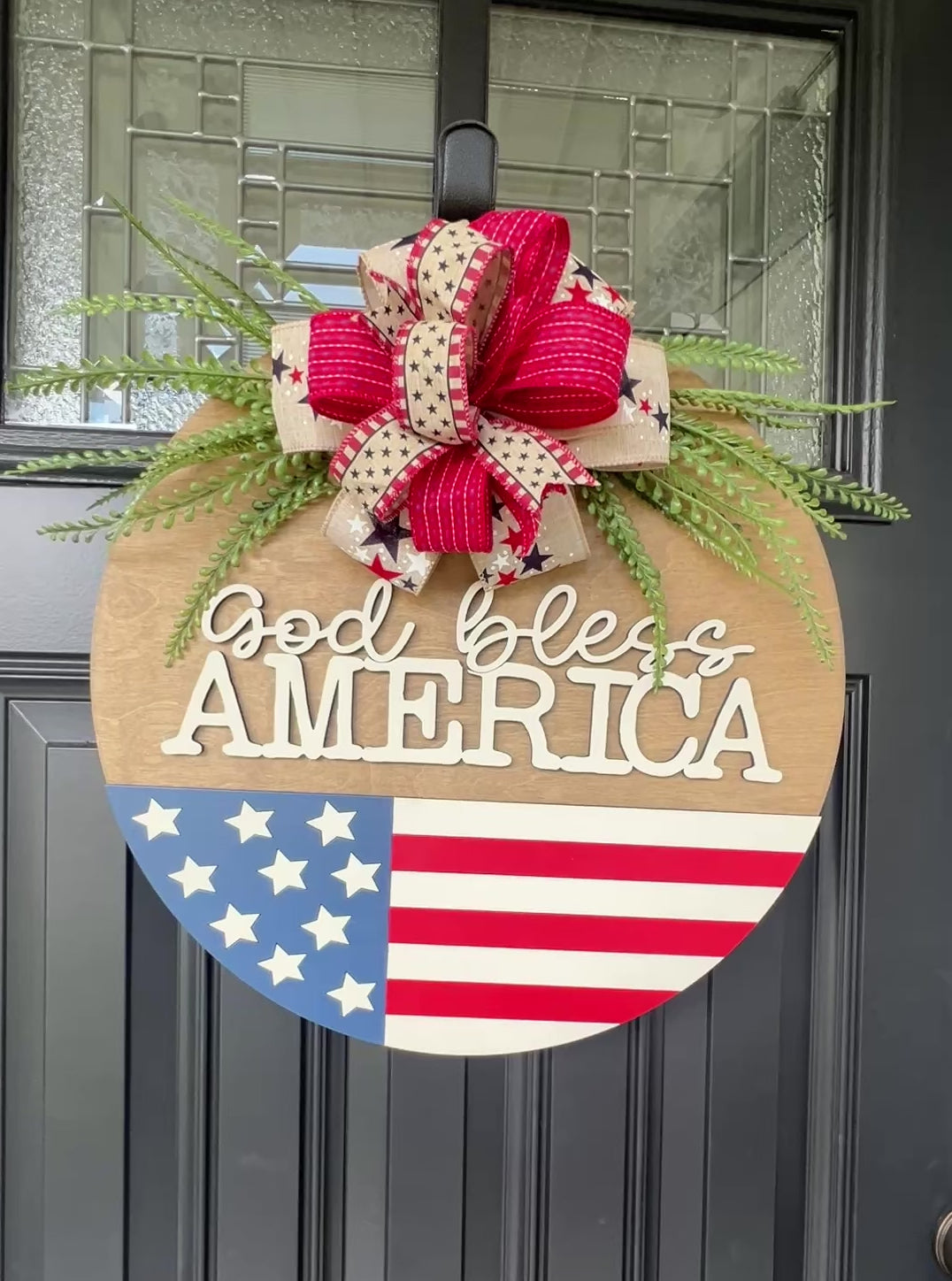 Decorative door hanger with 'God bless America' text and American flag design.