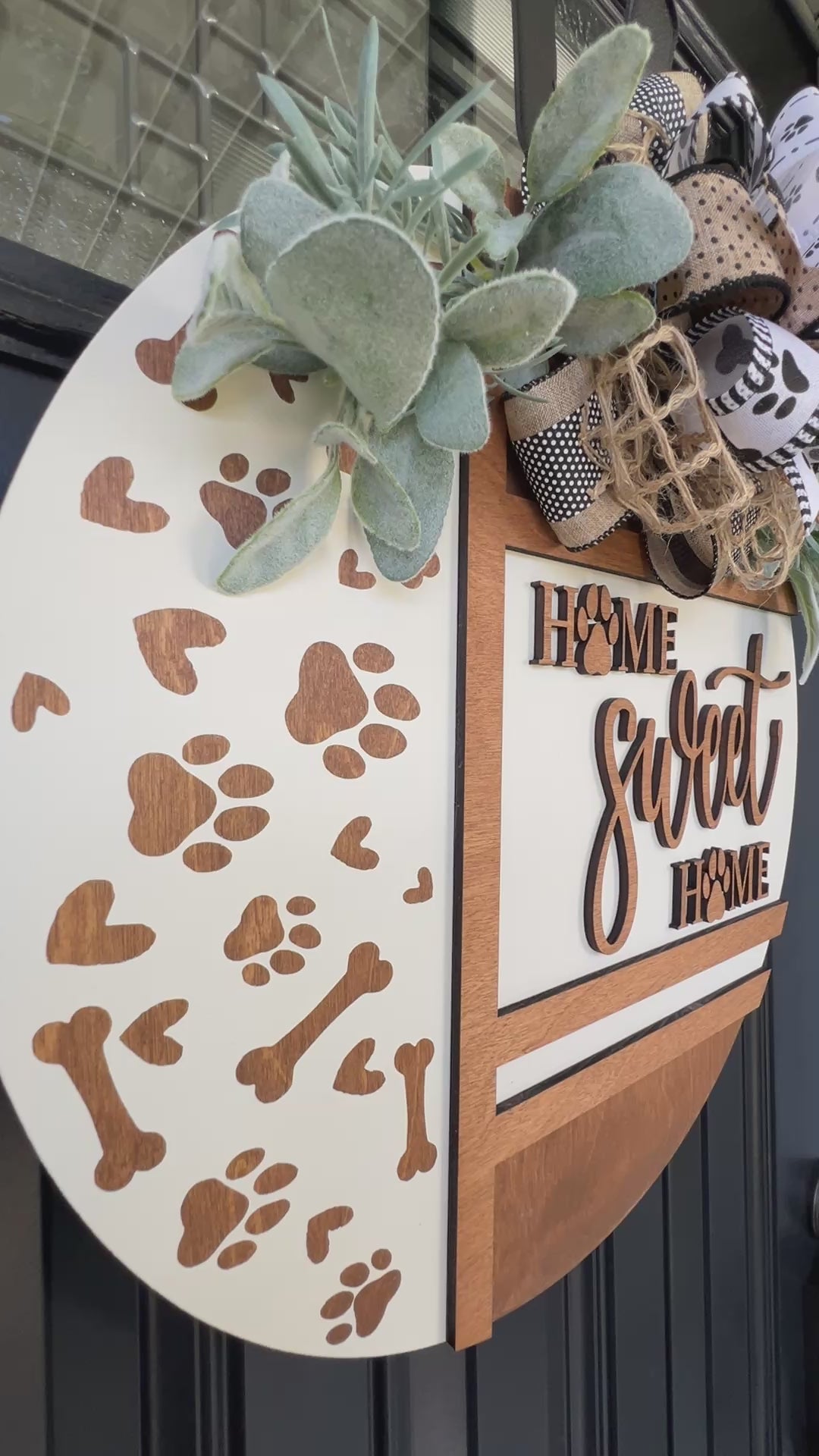 Handmade Home Sweet Home dog lover door hanger featuring laser-cut paw prints, dog bone accents, stained birchwood details, greenery, and a coordinating designer bow.