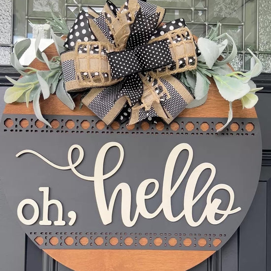 Close-up of premium black and cream designer bow with greenery on handcrafted wooden door sign.
Front view of modern farmhouse Oh Hello wooden welcome sign with dimensional lettering.