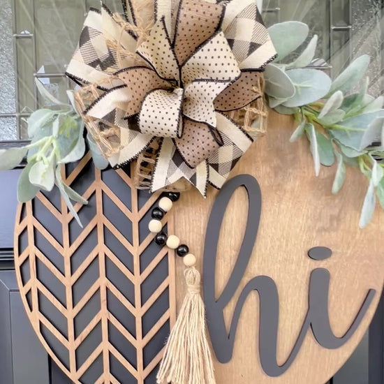 “Video showing handmade neutral ‘Hi’ layered wood door hanger displayed on a black front door”