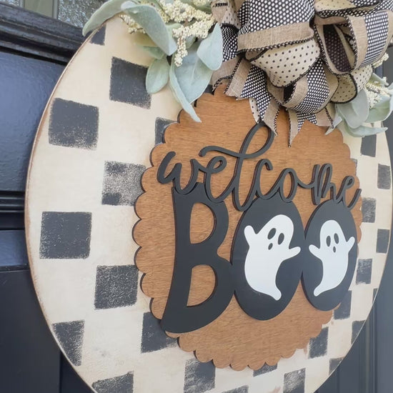 Handmade Welcome Boo Halloween door hanger with ghost accents, black and cream checkered background, layered wood lettering, designer bow, and fall front porch décor.