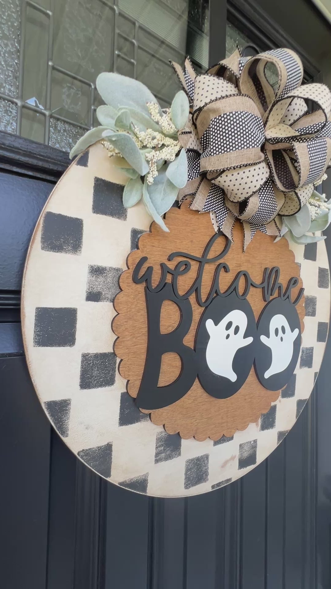 Handmade Welcome Boo Halloween door hanger with ghost accents, black and cream checkered background, layered wood lettering, designer bow, and fall front porch décor.