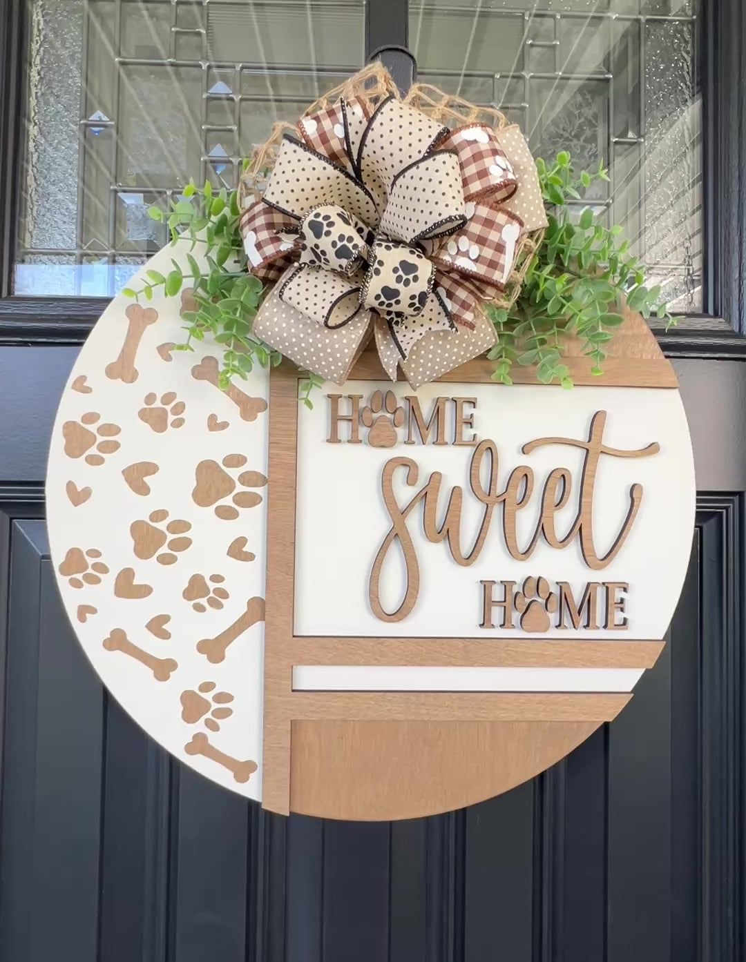 Handmade Home Sweet Home dog lover door hanger featuring laser-cut paw prints, dog bone accents, stained birchwood details, greenery, and a coordinating designer bow. 
