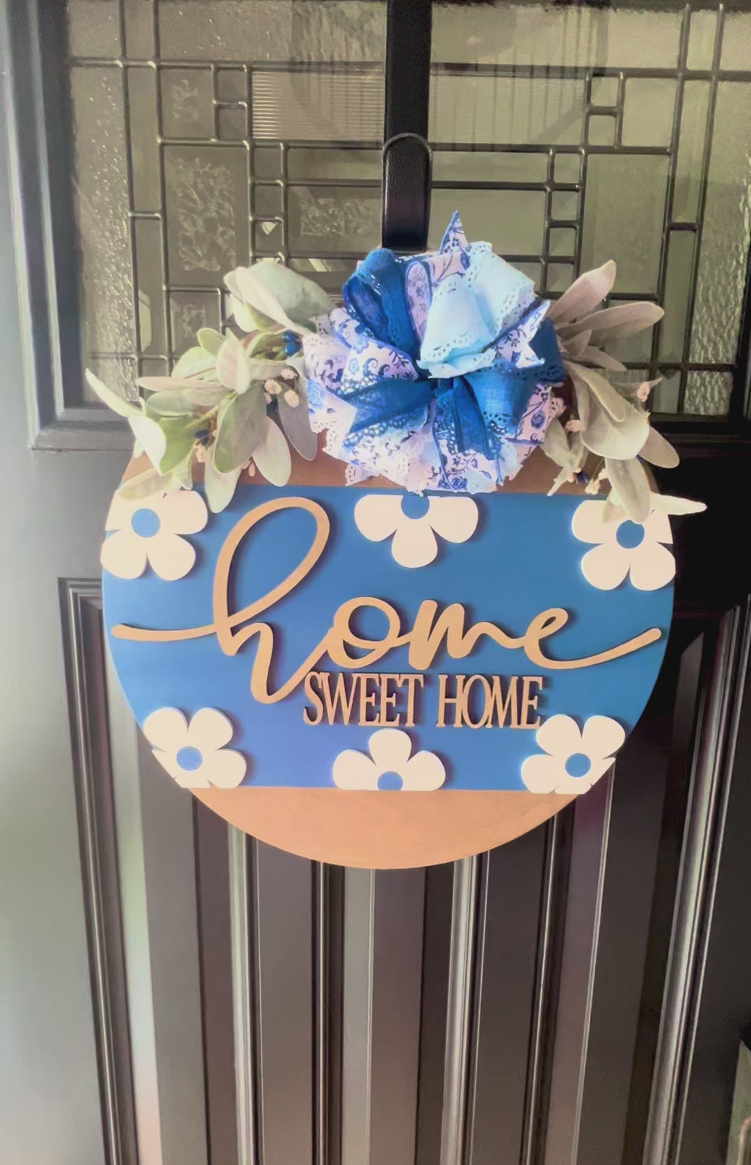 “Close-up of raised home sweet home lettering on blue floral door hanger”
“Blue and white bow with greenery on handmade home sweet home sign”