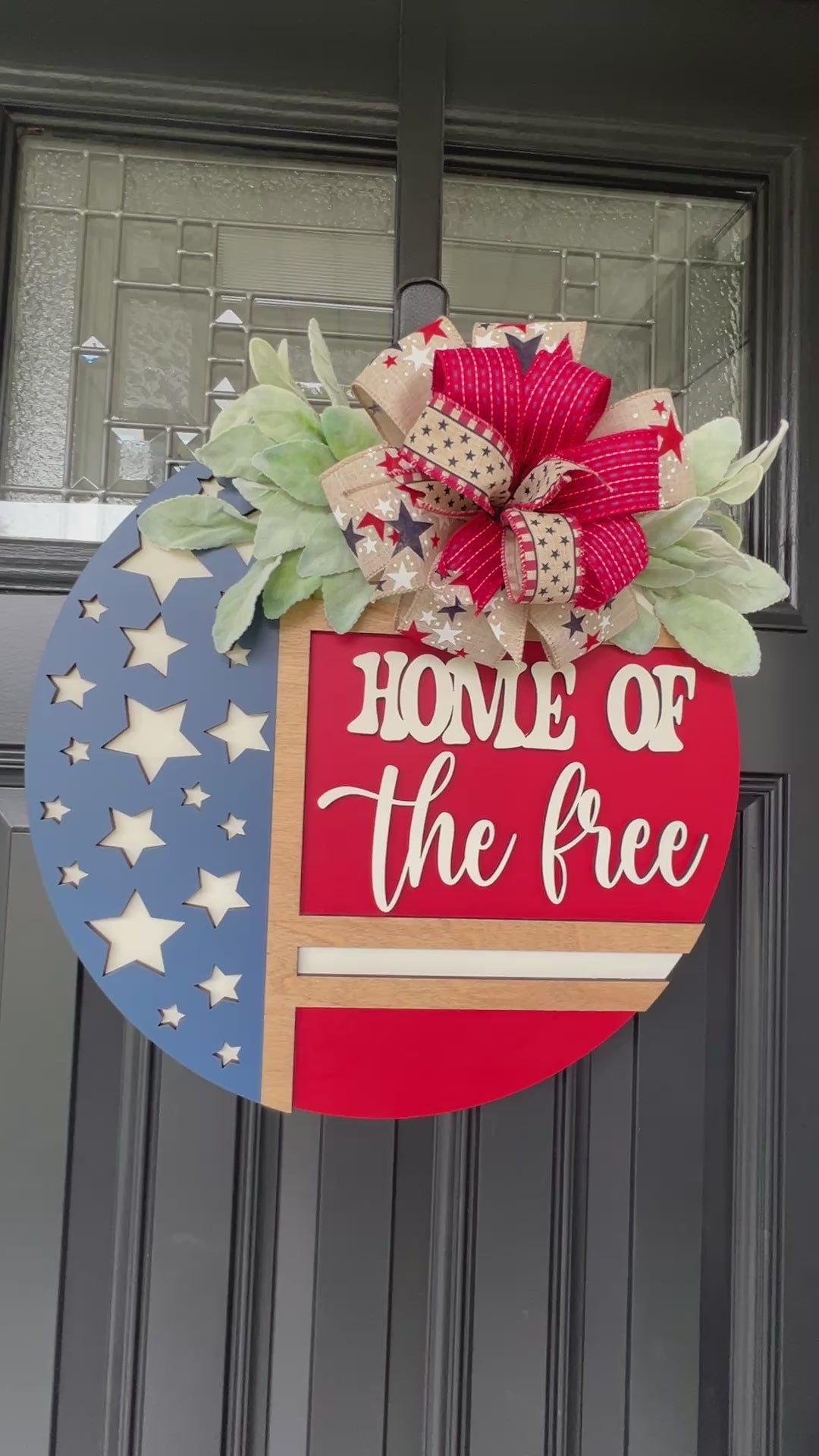Decorative door hanger with 'Home of the Free' text and American flag design.