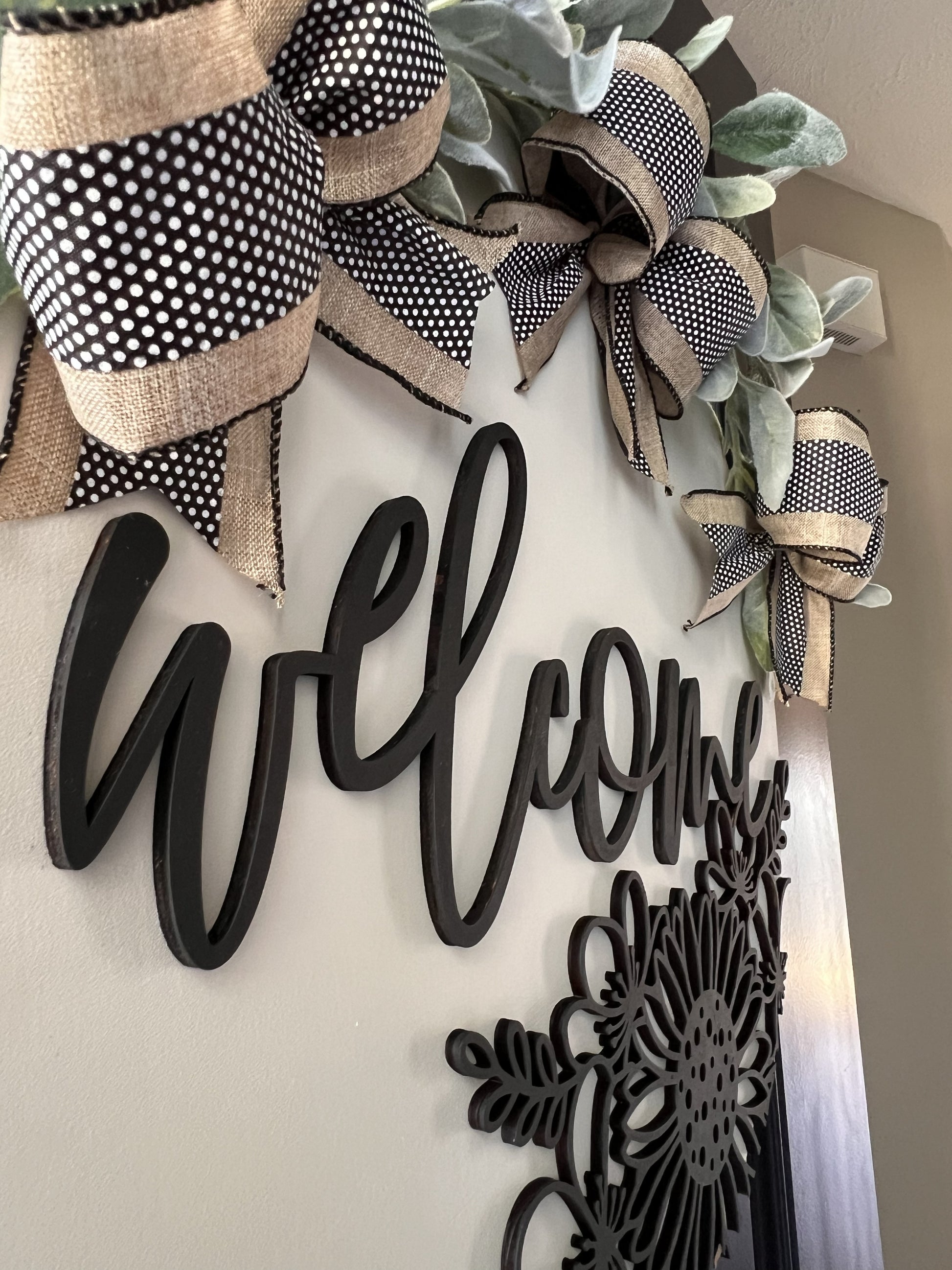 Decorative wreath with polka dot and burlap bows, 'Welcome' sign, with  floral design birchwood overlay on a neutral background.